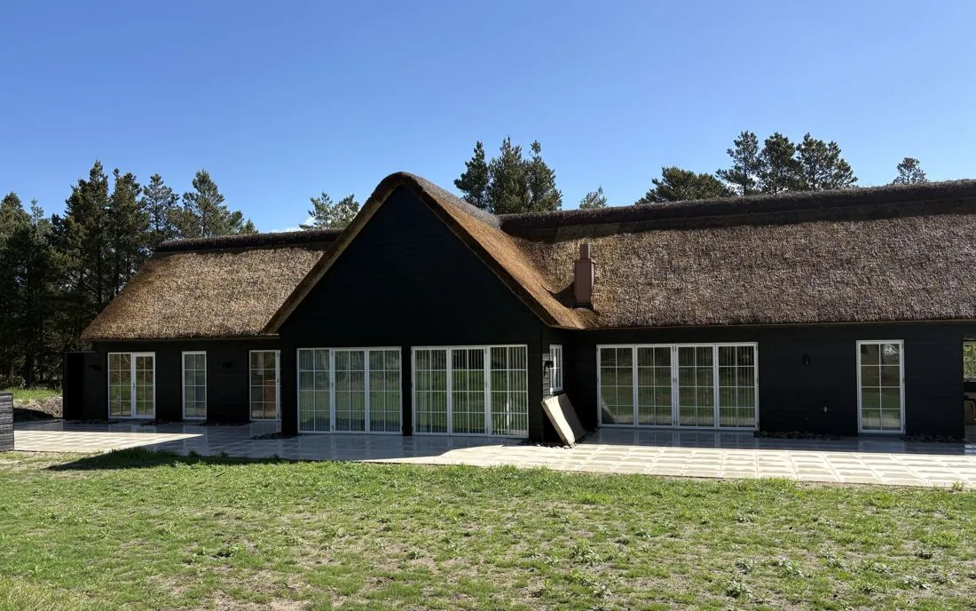 Sommerhus i badehotelstil med stråtag og sprossede vinduer, bygget af Vestkystens Byggefirma